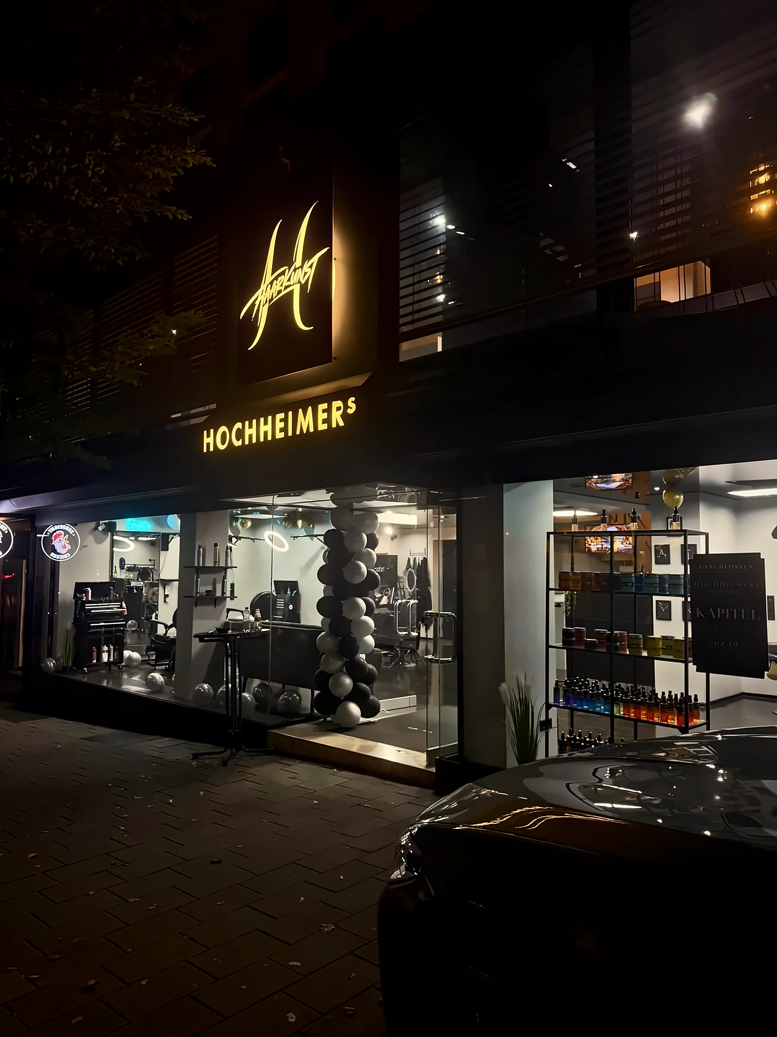 Ladenfront von HOCHHEIMERS Haarkunst in der Klarastraße bei Nacht